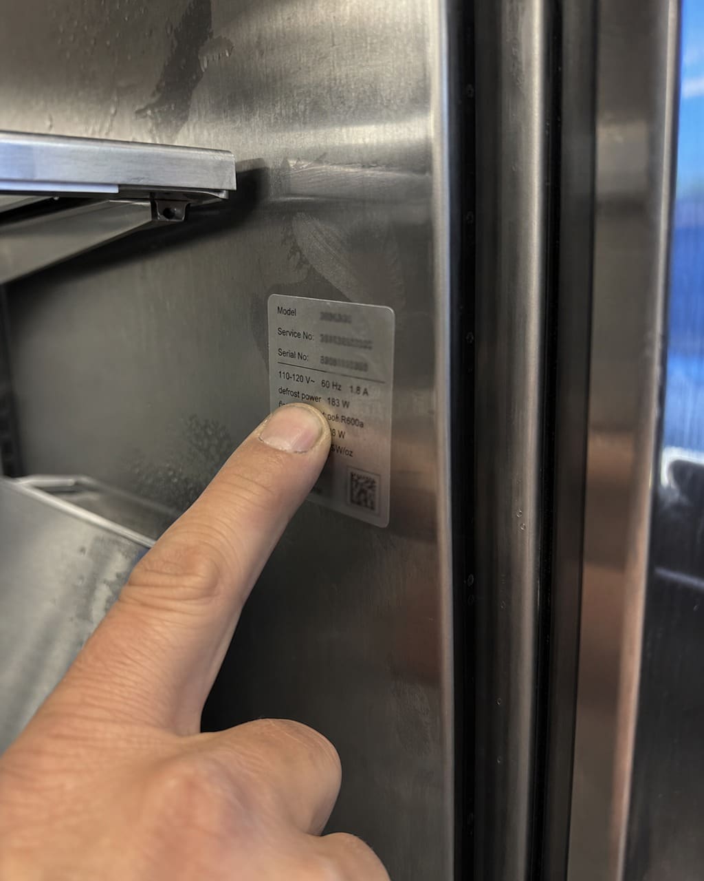 Close-up of a Sub-Zero model and serial number tag on the interior wall of a built-in refrigerator in a Cupertino kitchen